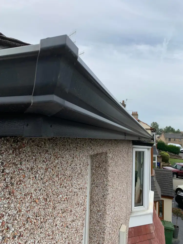 Black guttering fitted around the corner of a house