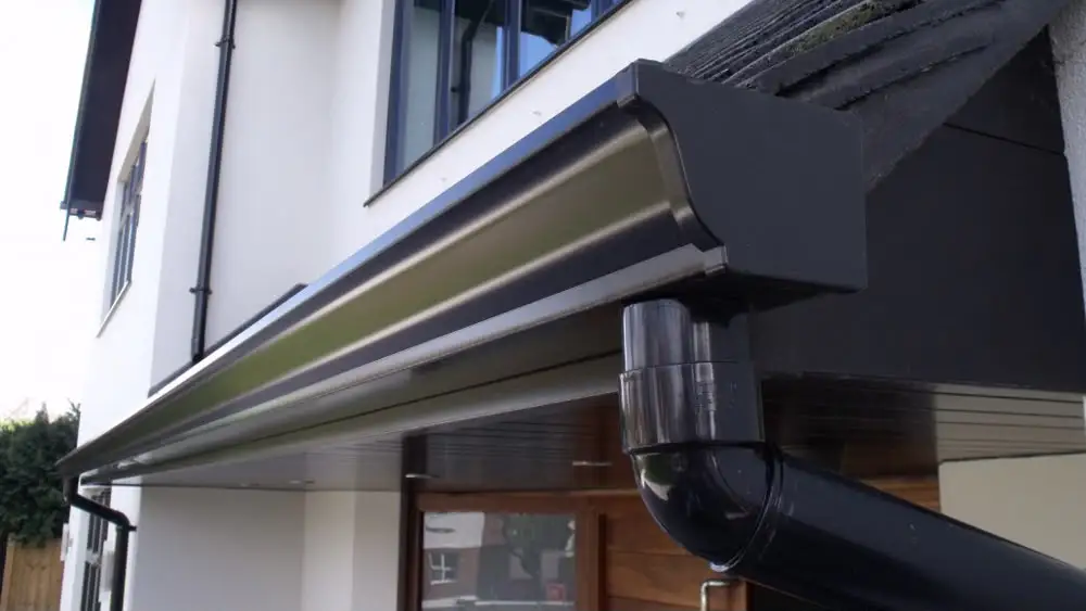 Completed black rainwater gutter and downpipe system on a house