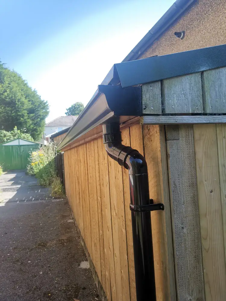 Black gutter and downpipe system fitted to a shed