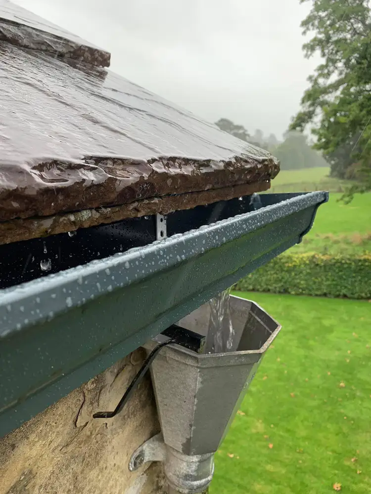 Rainwater gutter system fitted beneath a slate roof